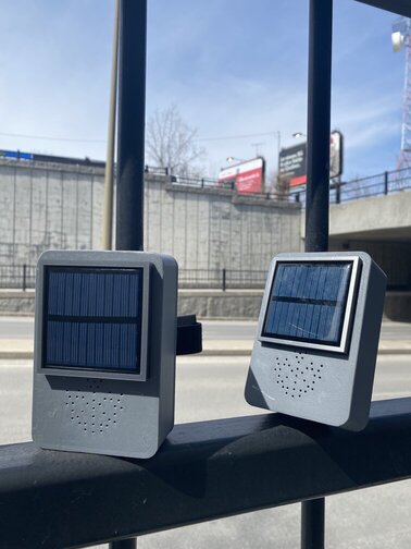 Two small, metallic speakers with solar cells attached on a window sill